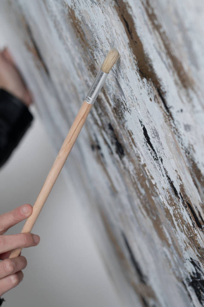 Close-up of a paintbrush stroking a canvas with fresh paint.