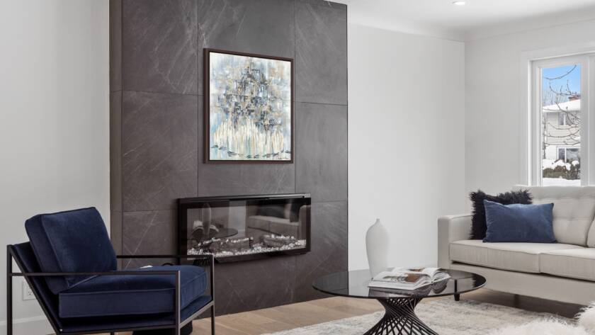 Mockup of "Wrapped in Faith, Bathed in Gold" painting hung above a sleek glass fireplace in a contemporary living room.