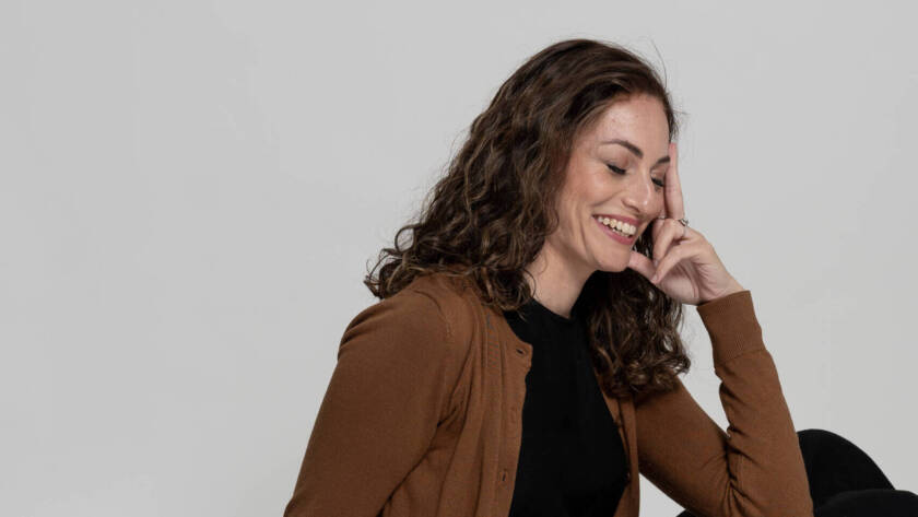 Jewish artist Chaya Koritz sitting on the floor and smiling.