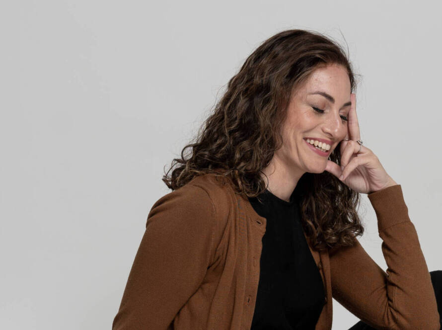 Jewish artist Chaya Koritz sitting on the floor and smiling.